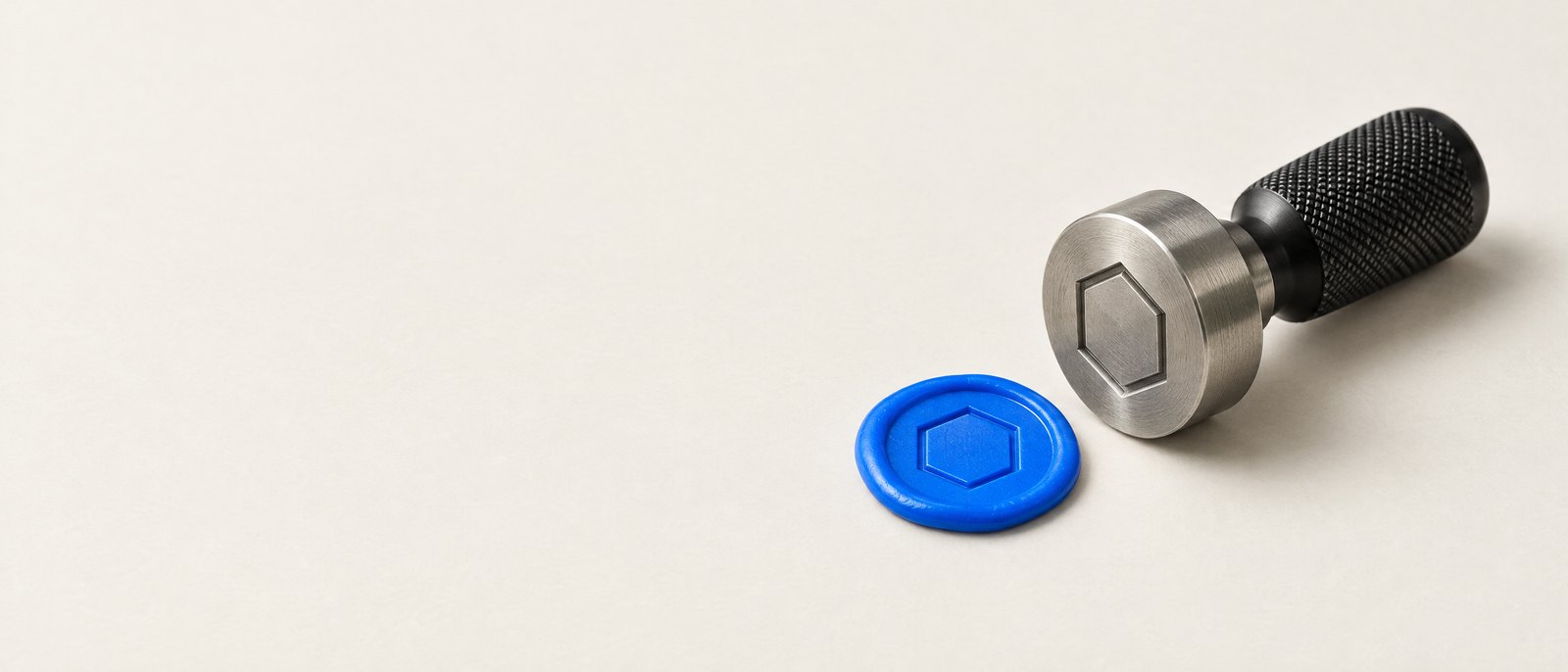 Brushed-steel seal stamp beside a blue wax seal — studio still life